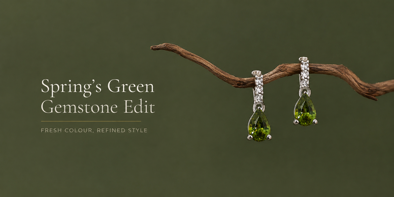 Stick holding two green gemstone pendant earrings. 
