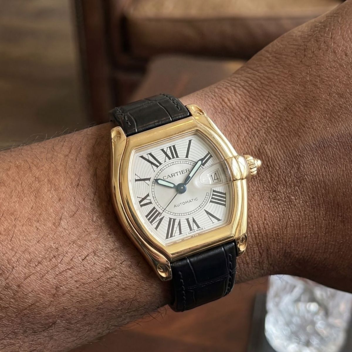 Cartier Roadster yellow gold watch on wrist with black leather strap