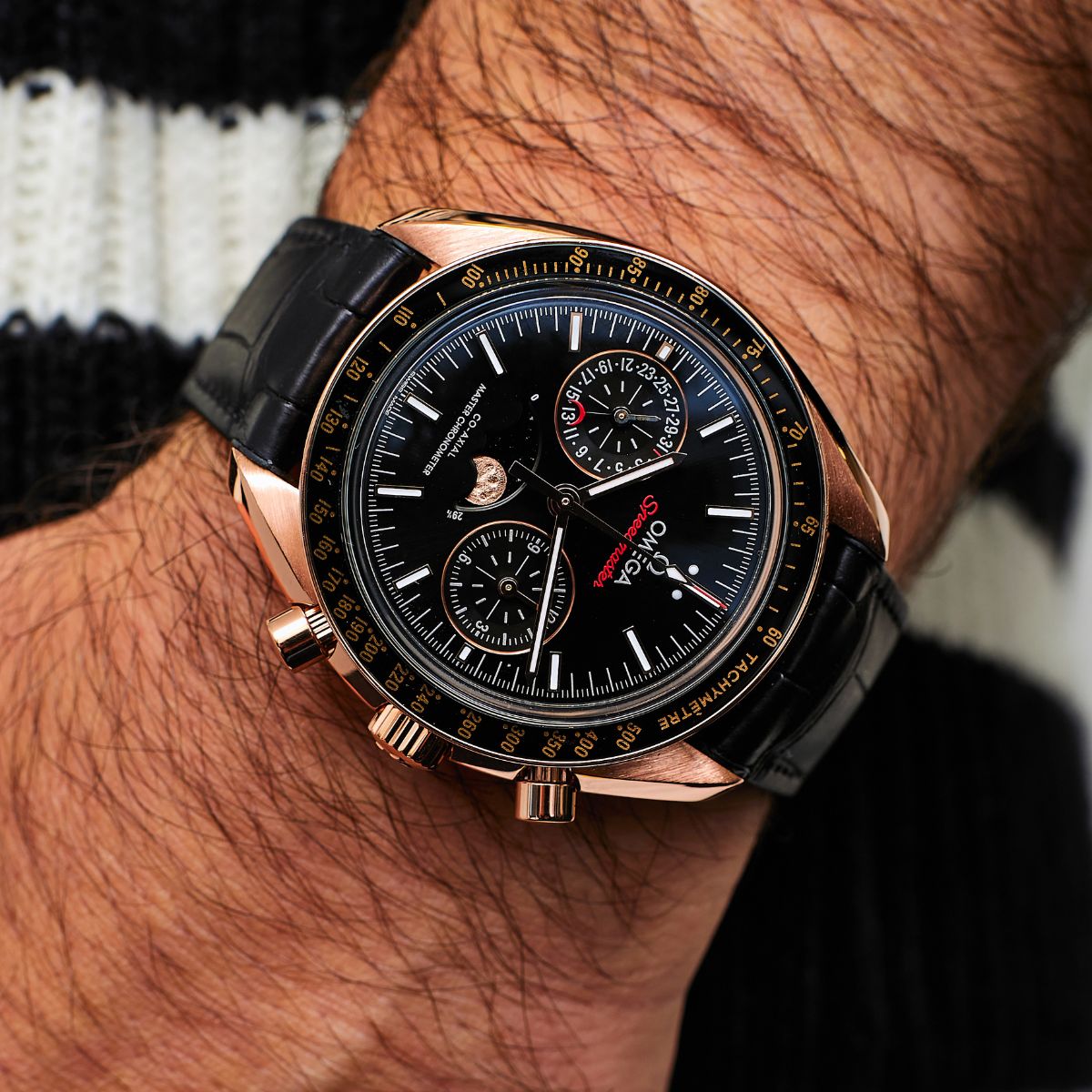 Omega Speedmaster Moonphase rose gold chronograph on black leather strap on wrist