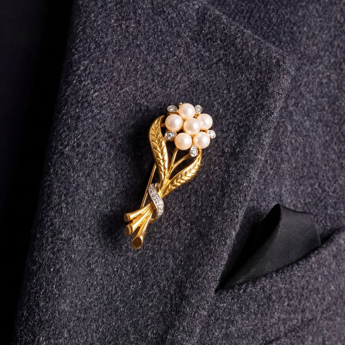 Gold pearl and diamond flower brooch on grey blazer